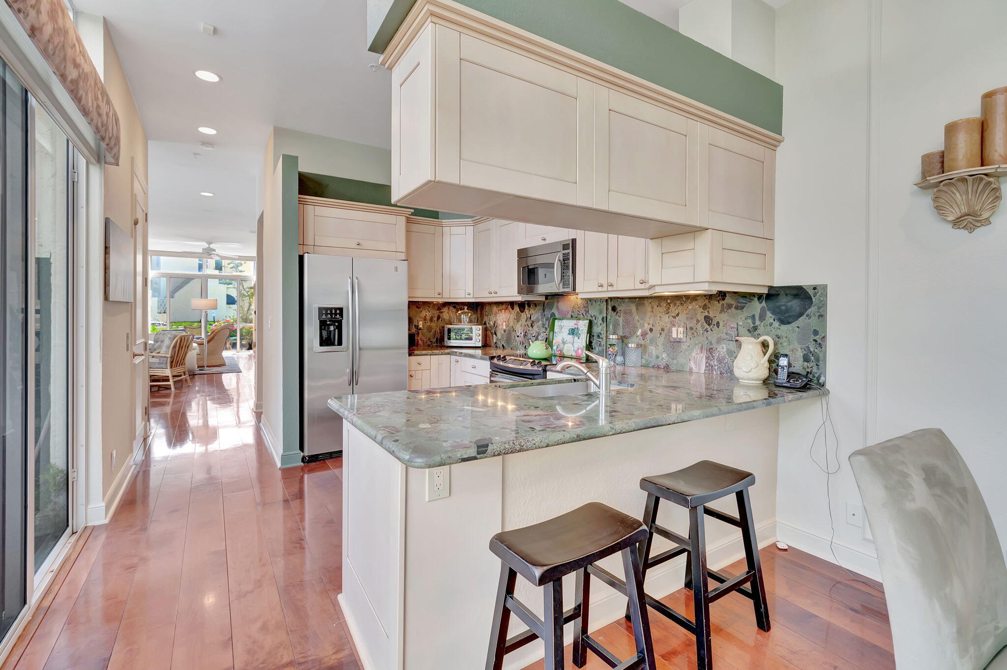 2115 South Ocean Boulevard, Unit 14 Delray Beach, FL 33483 - Photo 20 of 56 a kitchen with stainless steel appliances granite countertop a table chairs in it and wooden floors