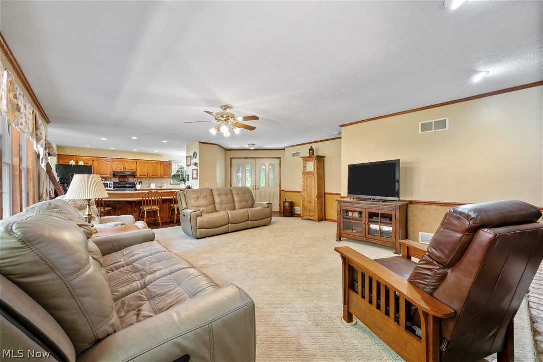 10400 Stoneacre Road Northwest Canal Fulton, OH 44614 - Photo 5 of 44 Living room featuring a wainscoted wall, a ceiling fan, recessed lighting, light colored carpet, and crown molding
