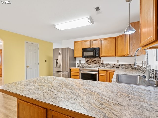 2488 Pheasant Ridge Street Umatilla, OR 97882 - Photo 9 of 40 a kitchen with stainless steel appliances granite countertop a sink stove and refrigerator