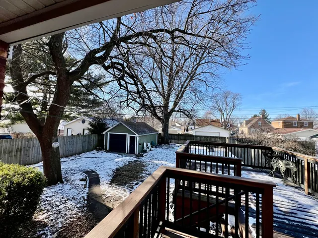 a view of a roof deck with wooden fence and large trees