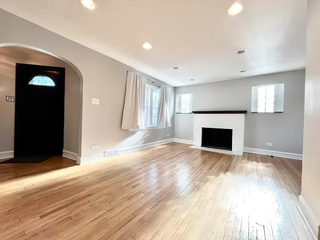a view of empty room with wooden floor and fireplace