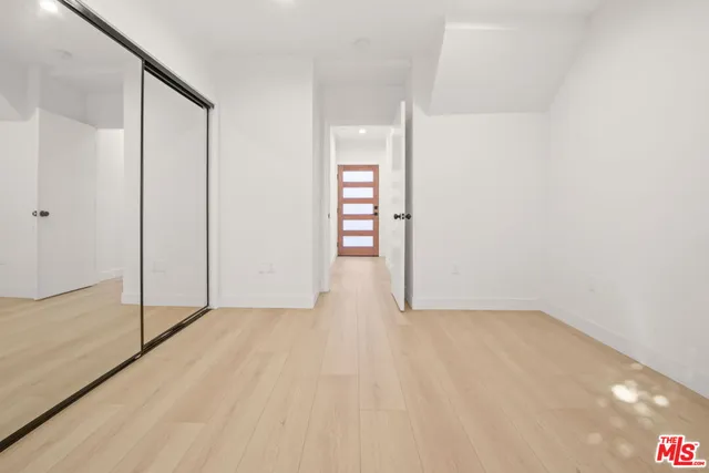 a view of an empty room with wooden floor and closet