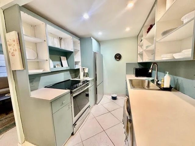 a kitchen with stainless steel appliances a stove a sink a microwave a refrigerator a cabinets and wooden floor