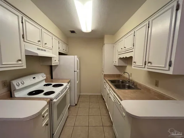 a kitchen that has a sink a stove and a refrigerator