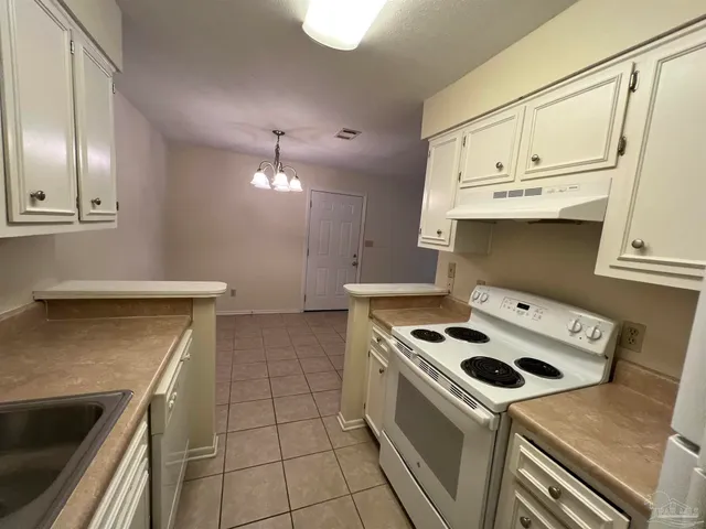 a kitchen with stainless steel appliances a stove a sink and white cabinets