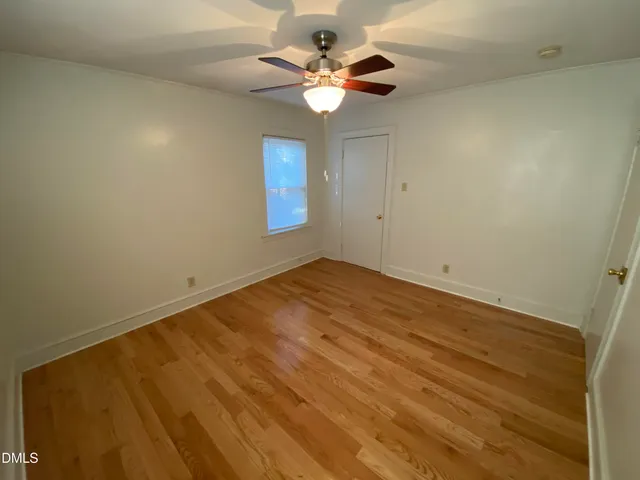 an empty room with a ceiling fan and a window
