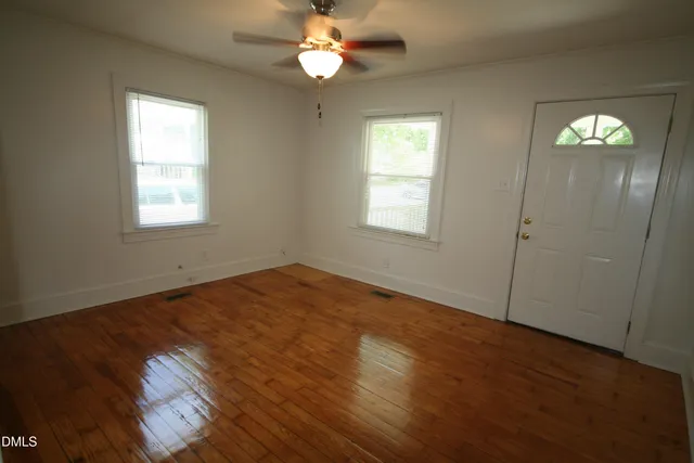 an empty room with windows and fan