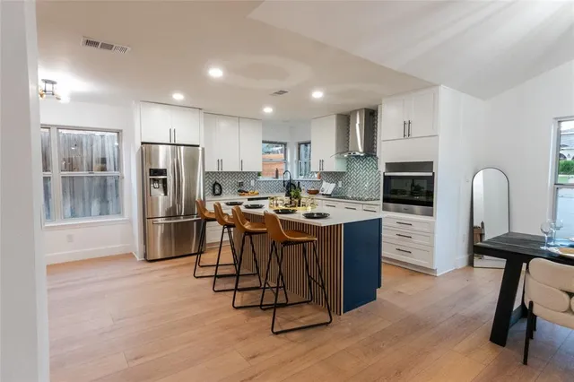 a kitchen with stainless steel appliances kitchen island granite countertop a refrigerator a stove a sink a washer and island with wooden floor