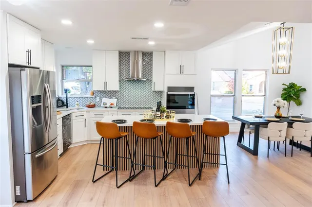 a kitchen with stainless steel appliances granite countertop a dining table chairs refrigerator sink and cabinets