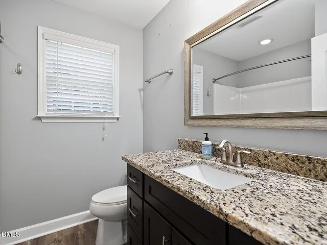 a bathroom with a granite countertop sink a toilet and a mirror