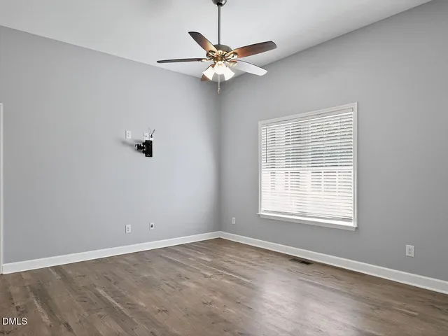 an empty room with a window and a fan