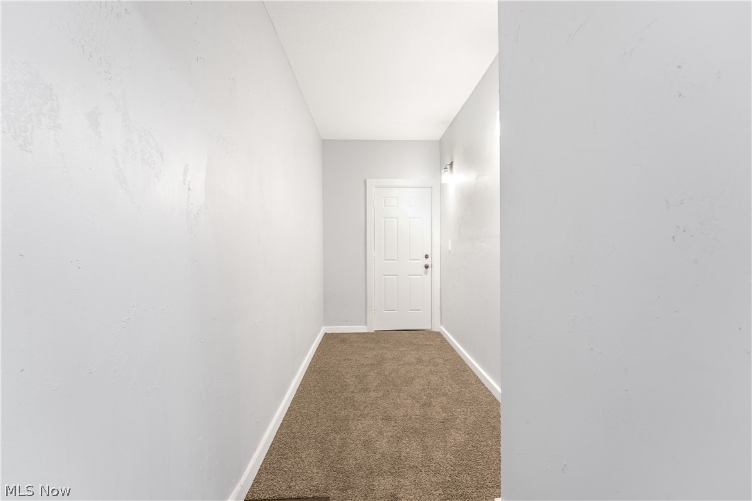885 Wales Road Northeast Massillon, OH 44646 - Photo 12 of 34 Entryway featuring a paneled door, neutral wall paint, white baseboards, and brown carpet flooring