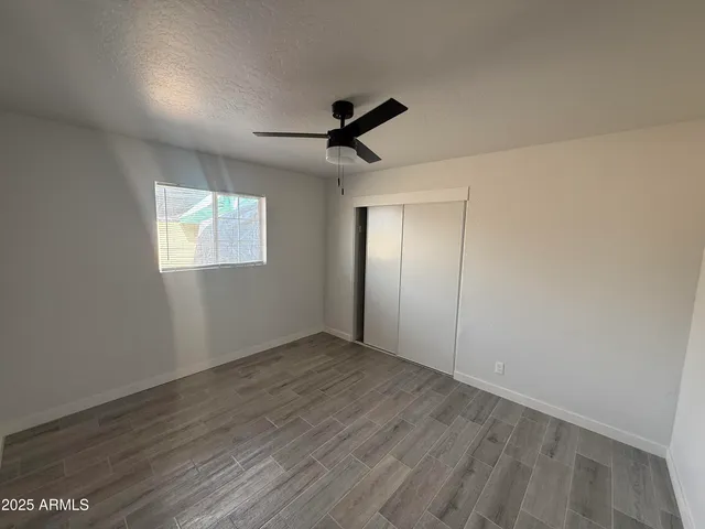 an empty room with wooden floor ceiling fan and windows