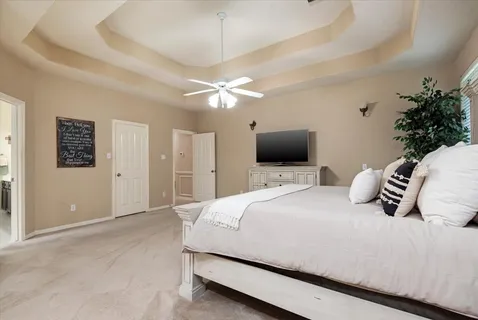 a bedroom with a bed flat screen tv and a chandelier