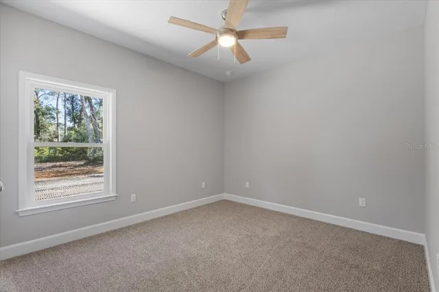 an empty room with a window and a ceiling fan