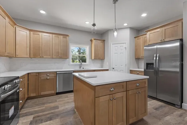 a kitchen with a sink a stove a refrigerator cabinets and a window