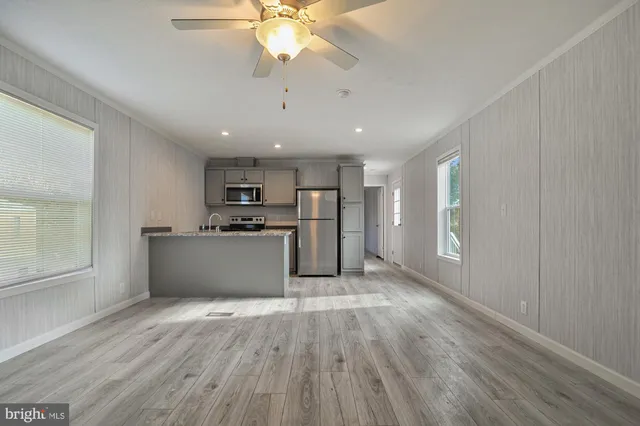 a view of kitchen with stainless steel appliances refrigerator stove and wooden floor