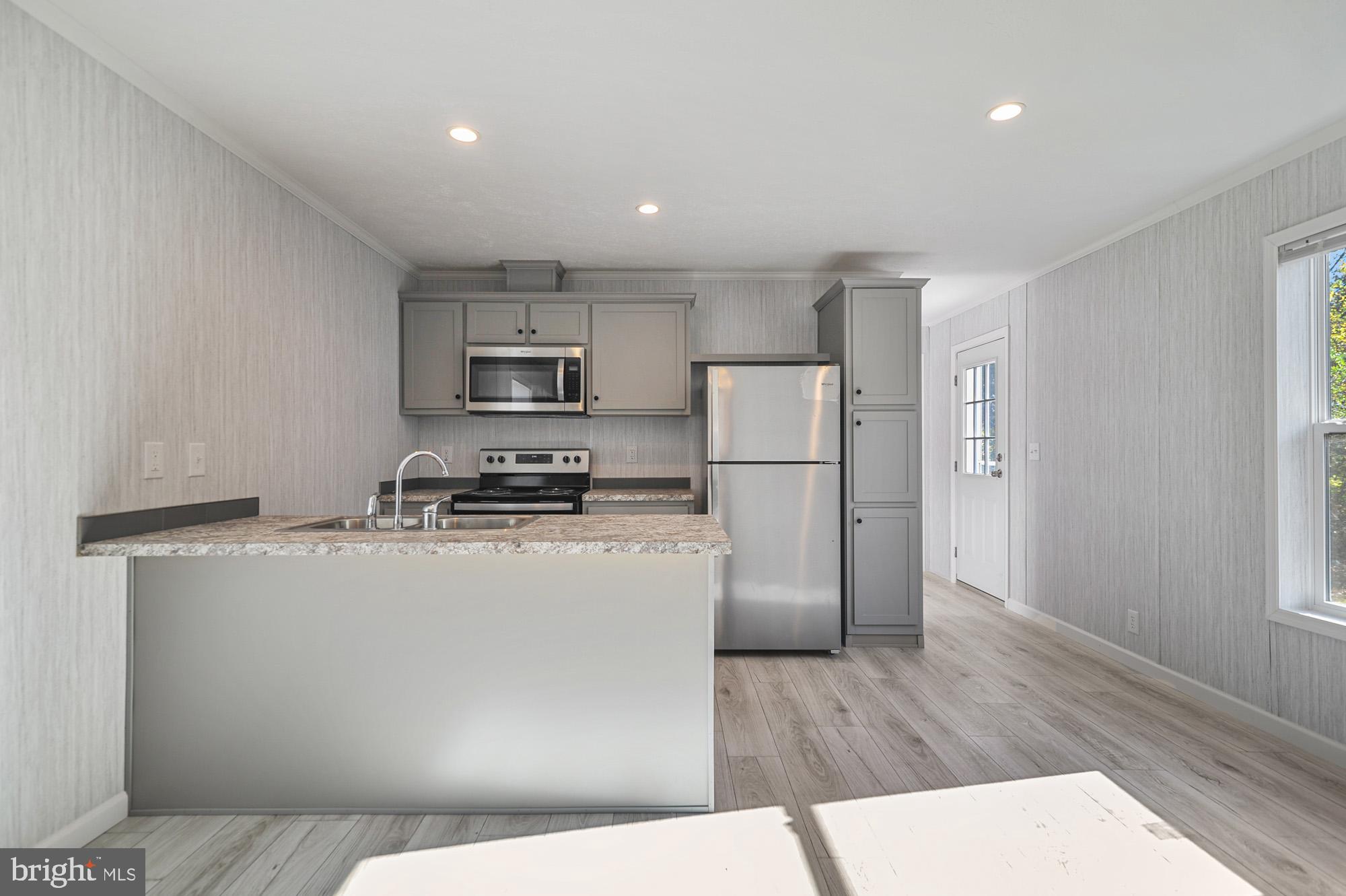 1061 South Little Creek Road, Unit 207 Dover, DE 19901 - Photo 10 of 20 a kitchen with a refrigerator a stove top oven and a counter space