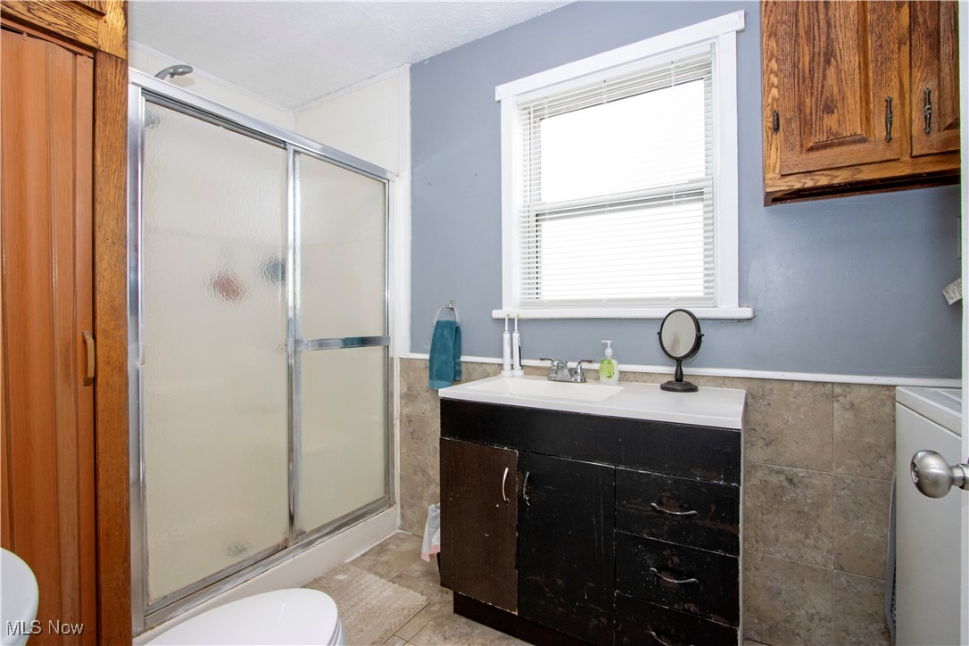 53 Grant Street Rittman, OH 44270 - Photo 22 of 34 Full bathroom with vanity, a shower stall, wainscoting, tile walls, and washer / clothes dryer