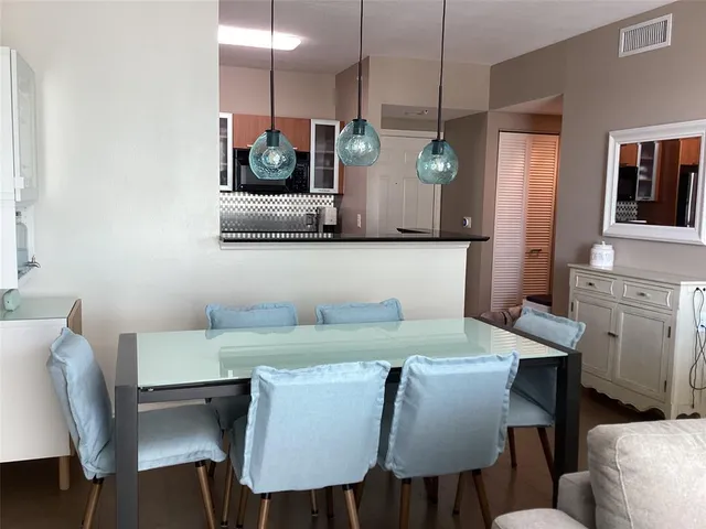 a view of kitchen with stainless steel appliances granite countertop dining table chairs and a refrigerator