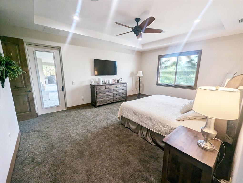 710 Albee Road West Nokomis, FL 34275 - Photo 19 of 30 a spacious bedroom with a bed a couch and a flat screen tv