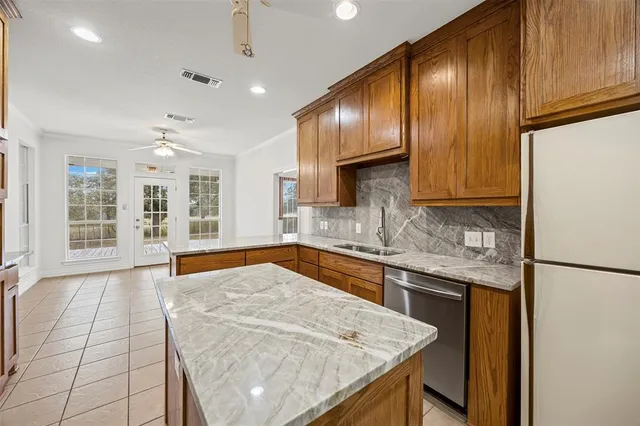 a kitchen with stainless steel appliances granite countertop wooden cabinets a refrigerator and a sink