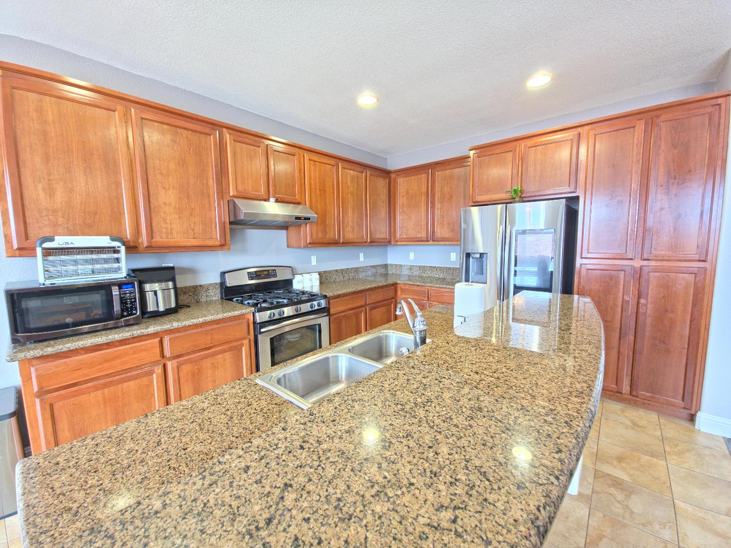 11724 Brook Valley Way Rancho Cordova, CA 95742 - Photo 3 of 32 a kitchen with stainless steel appliances granite countertop a refrigerator a stove a sink dishwasher with a dining table and chair