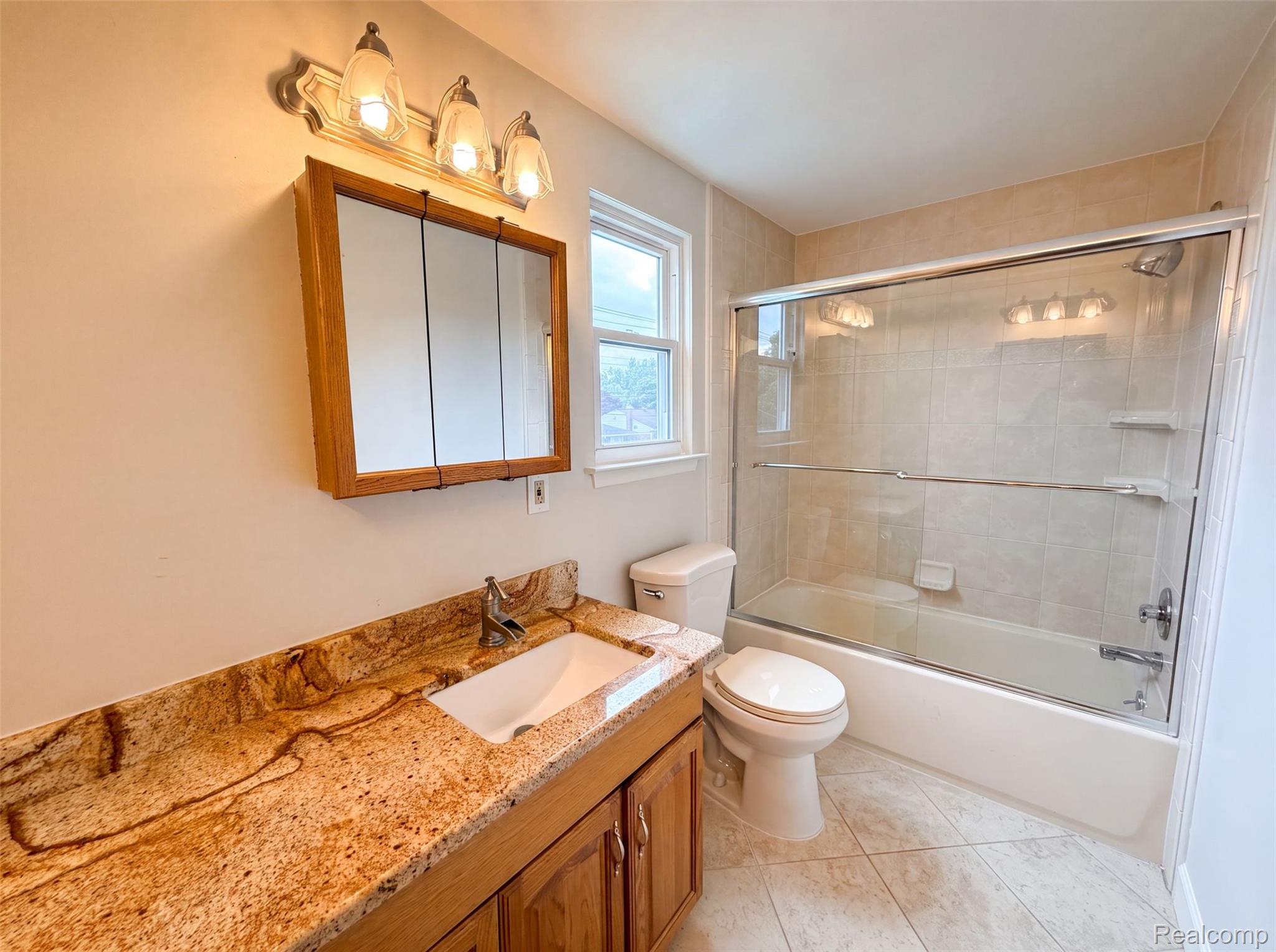 14729 Moran Road Allen Park, MI 48101 - Photo 12 of 17 Bathroom featuring a granite vanity with an undermount sink, a three-door medicine cabinet, and overhead three-bulb vanity lighting