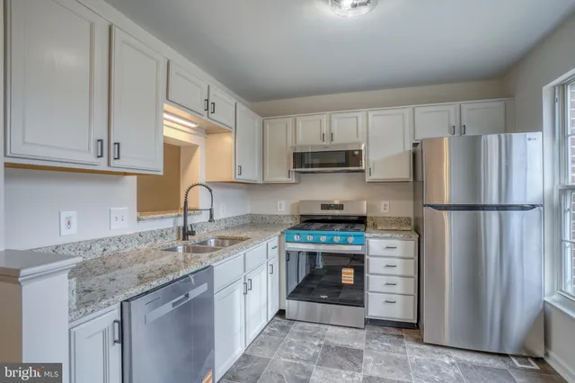 a kitchen with stainless steel appliances granite countertop a refrigerator sink and stove