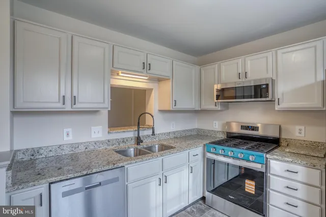 a kitchen with granite countertop white cabinets and a sink