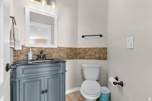1417 Blacksmith Lane Draper, UT 84020 - Photo 19 of 57 Bathroom featuring a gray vanity with a built-in sink, dark countertop, and mosaic tile backsplash