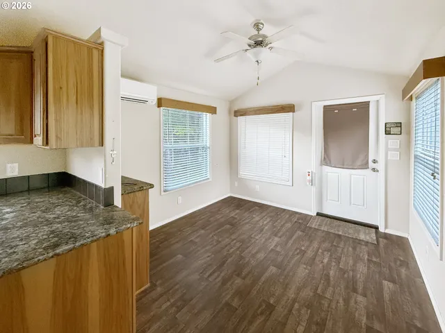 a view of a livingroom with wooden floor and kitchen space