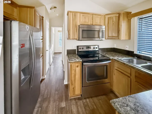 a kitchen with granite countertop a refrigerator stove and microwave