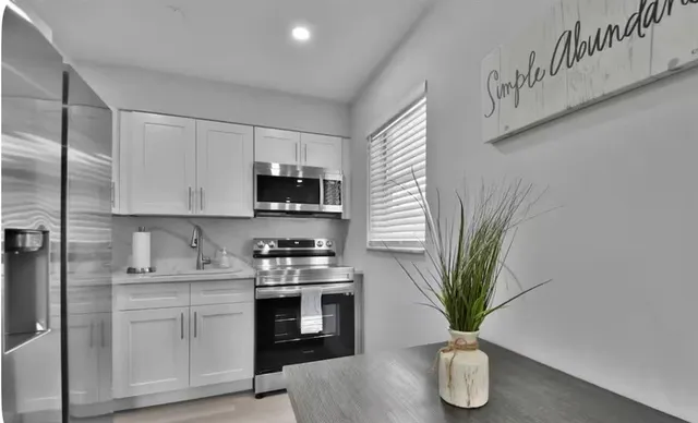 a kitchen with stainless steel appliances a white stove top oven a counter space and cabinets