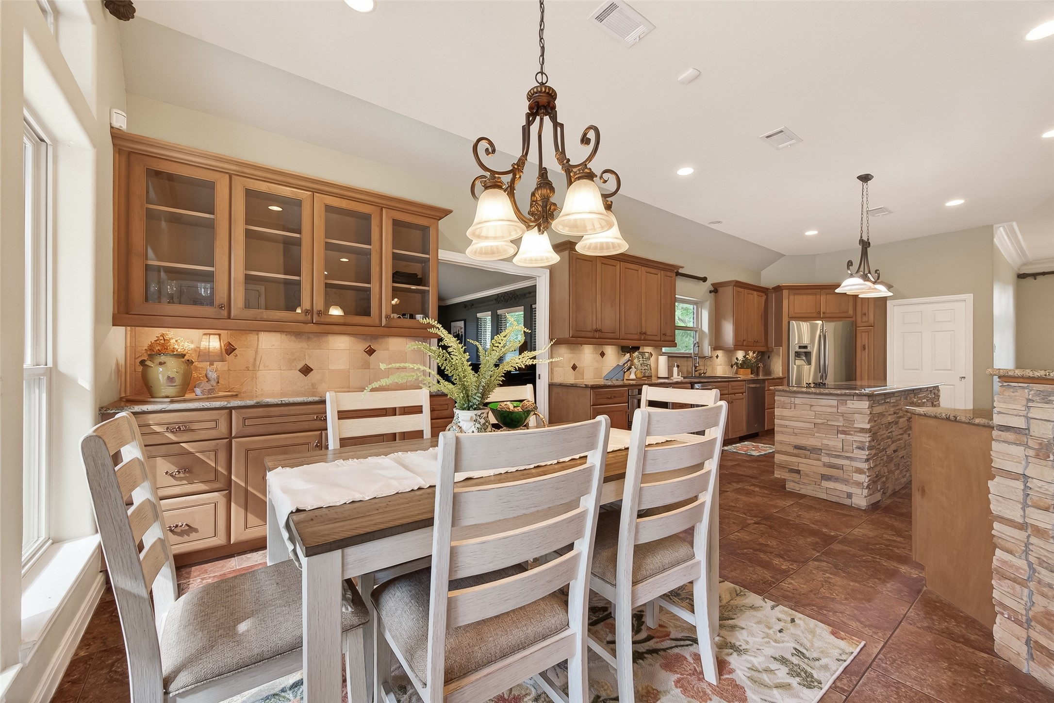 17603 Bending Cypress Road Cypress, TX 77429 - Photo 21 of 43 The inviting kitchen and dining area features warm wood cabinetry, a stone-accented island, and stylish pendant lighting. The open layout offers ample space for entertaining, with a large window providing natural light.