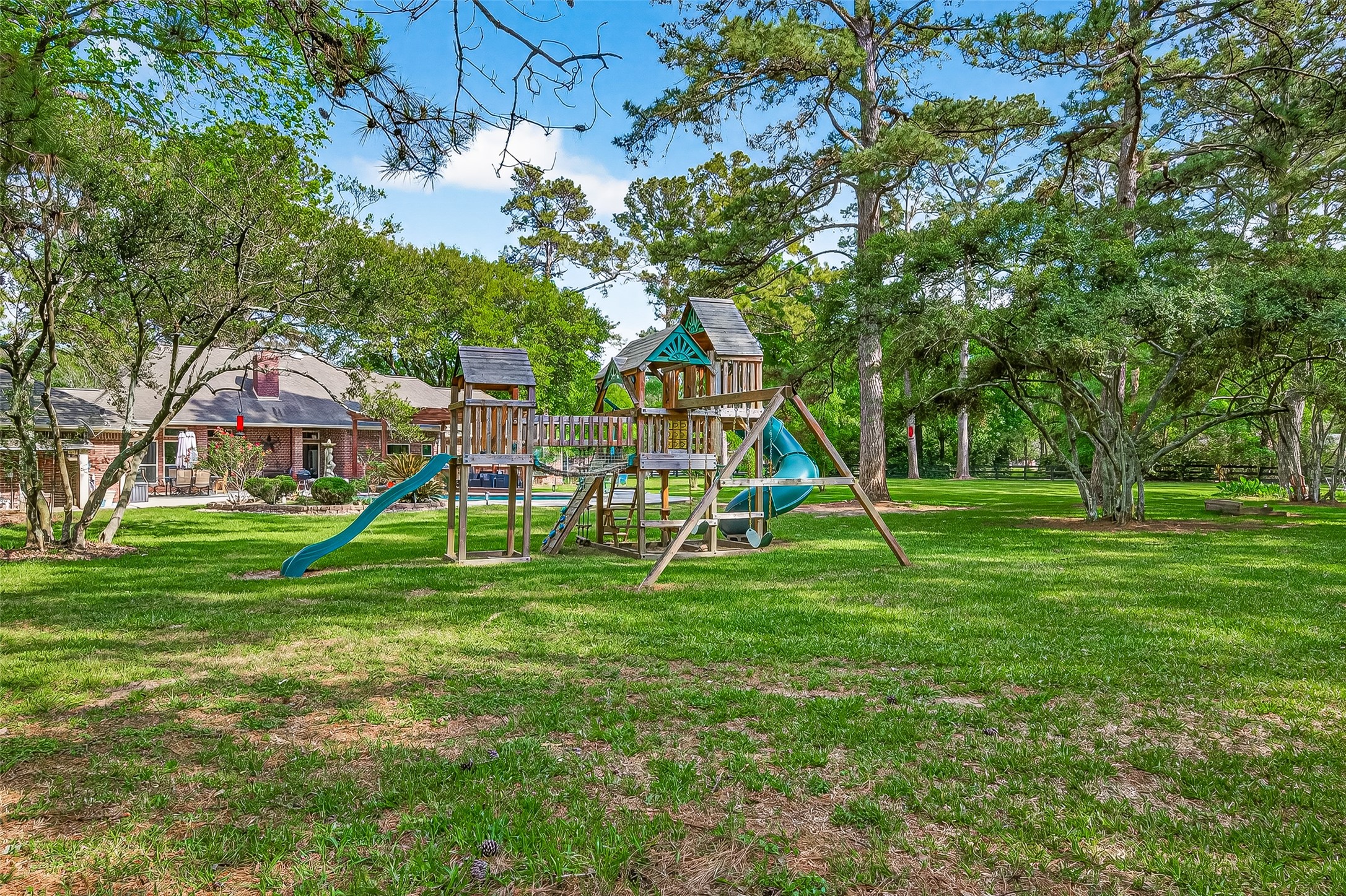 17603 Bending Cypress Road Cypress, TX 77429 - Photo 41 of 43 The spacious backyard features a wooden playground set surrounded by lush greenery and mature trees, providing a serene, family-friendly outdoor space.
