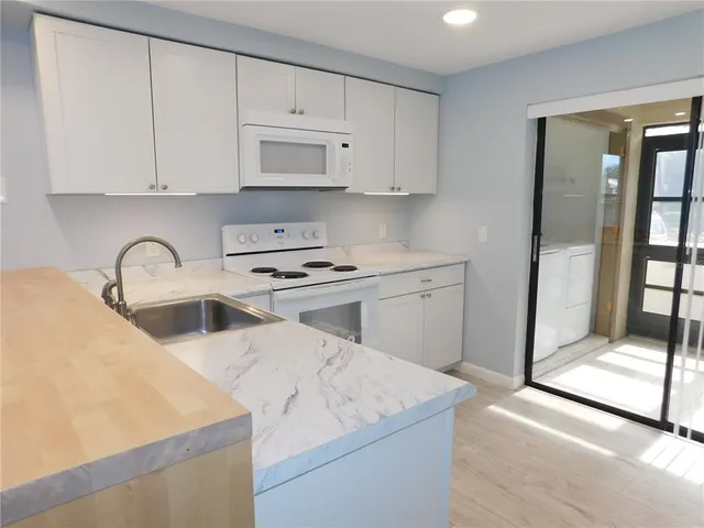 a kitchen with granite countertop white cabinets and white appliances