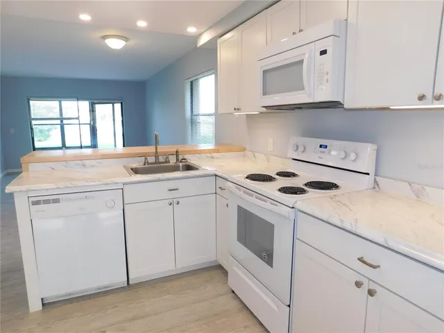 a kitchen with granite countertop white cabinets sink and white appliances