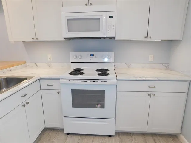a kitchen with white cabinets and white appliances