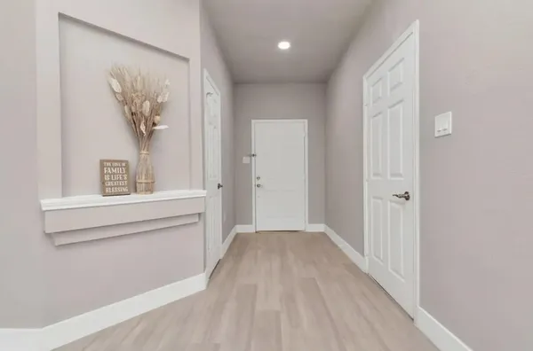 a view of a hallway with wooden floor and a bathroom