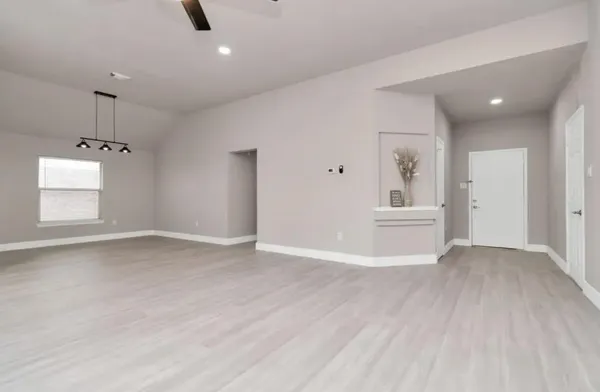 a view of an empty room with a window and wooden floor