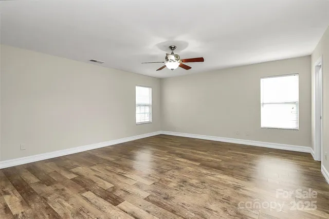 a view of an empty room with a ceiling fan and window