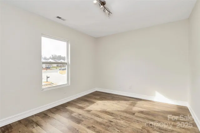 an empty room with wooden floor and bathroom view