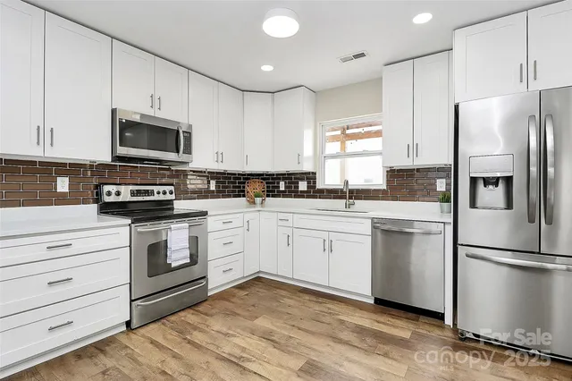 a kitchen with white cabinets and stainless steel appliances