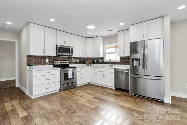 a kitchen with white cabinets and stainless steel appliances