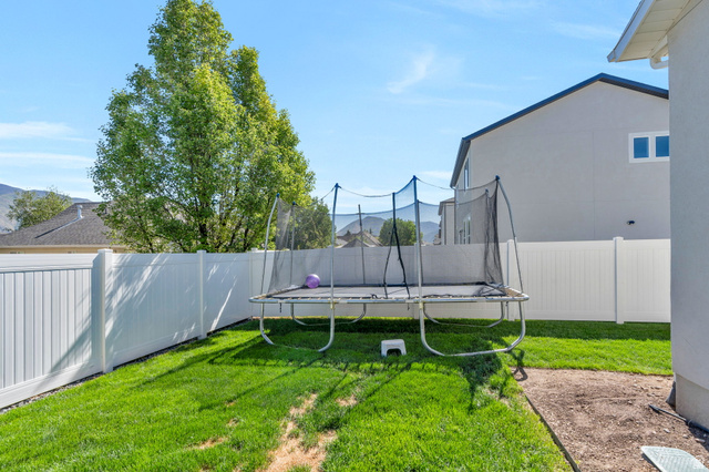 2664 West Maple Street Mapleton, UT 84664 - Photo 44 of 49 Expansive backyard featuring a white vinyl privacy fence, a verdant lawn, and a mature tree providing natural shade