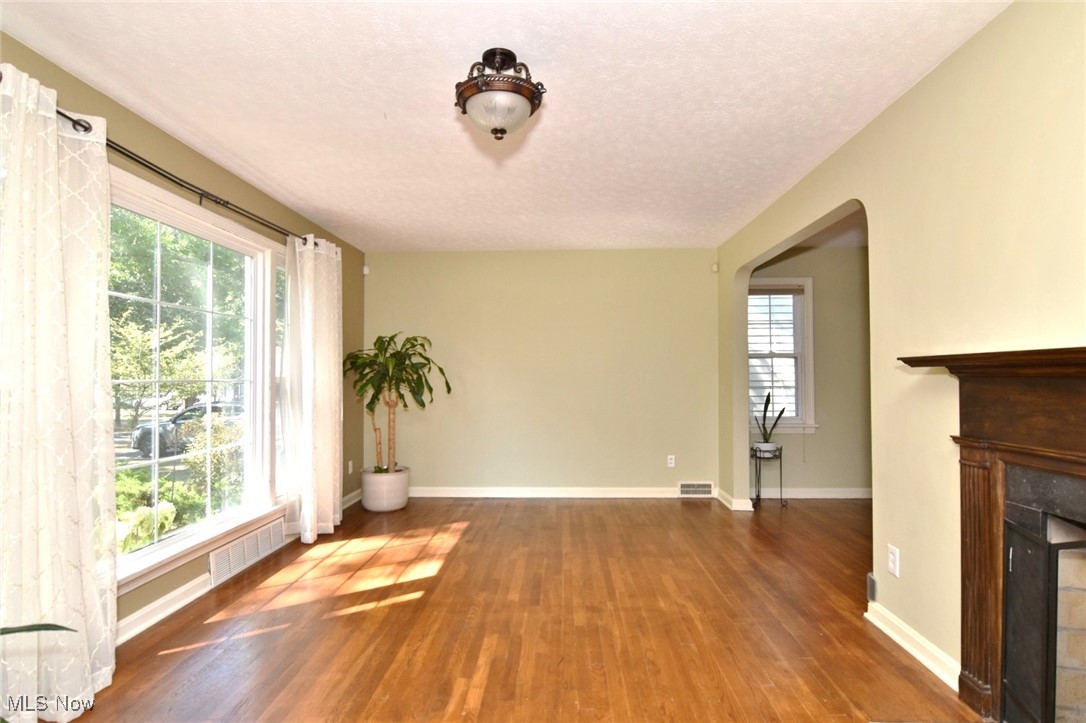 3679 Fenley Road Cleveland Heights, OH 44121 - Photo 6 of 45 Unfurnished living room with arched walkways, wood finished floors, a fireplace, and a textured ceiling