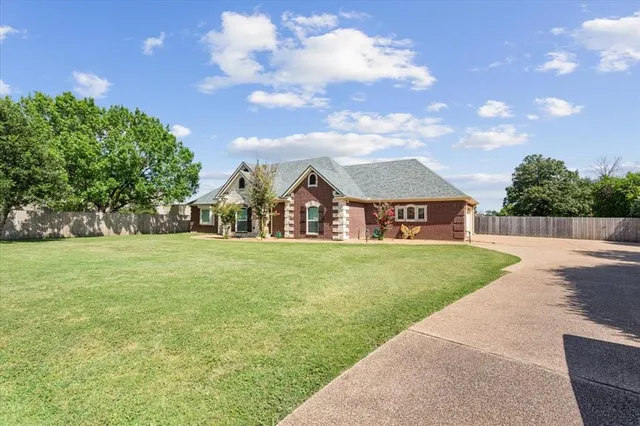 a view of a big house with a big yard and large trees
