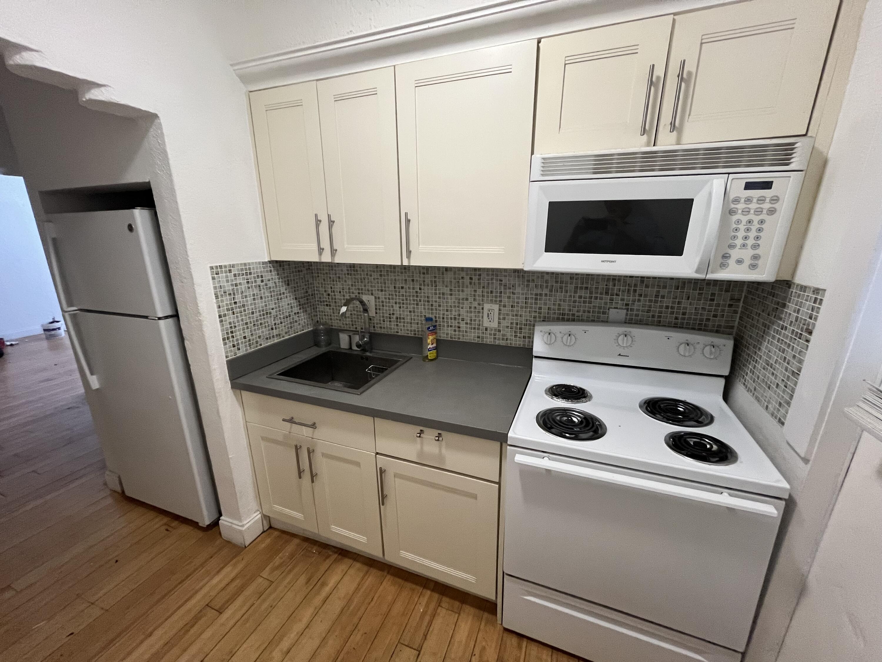 320 80th Street, Unit 4 Miami Beach, FL 33141 - Photo 1 of 11 a kitchen with a refrigerator sink and cabinets
