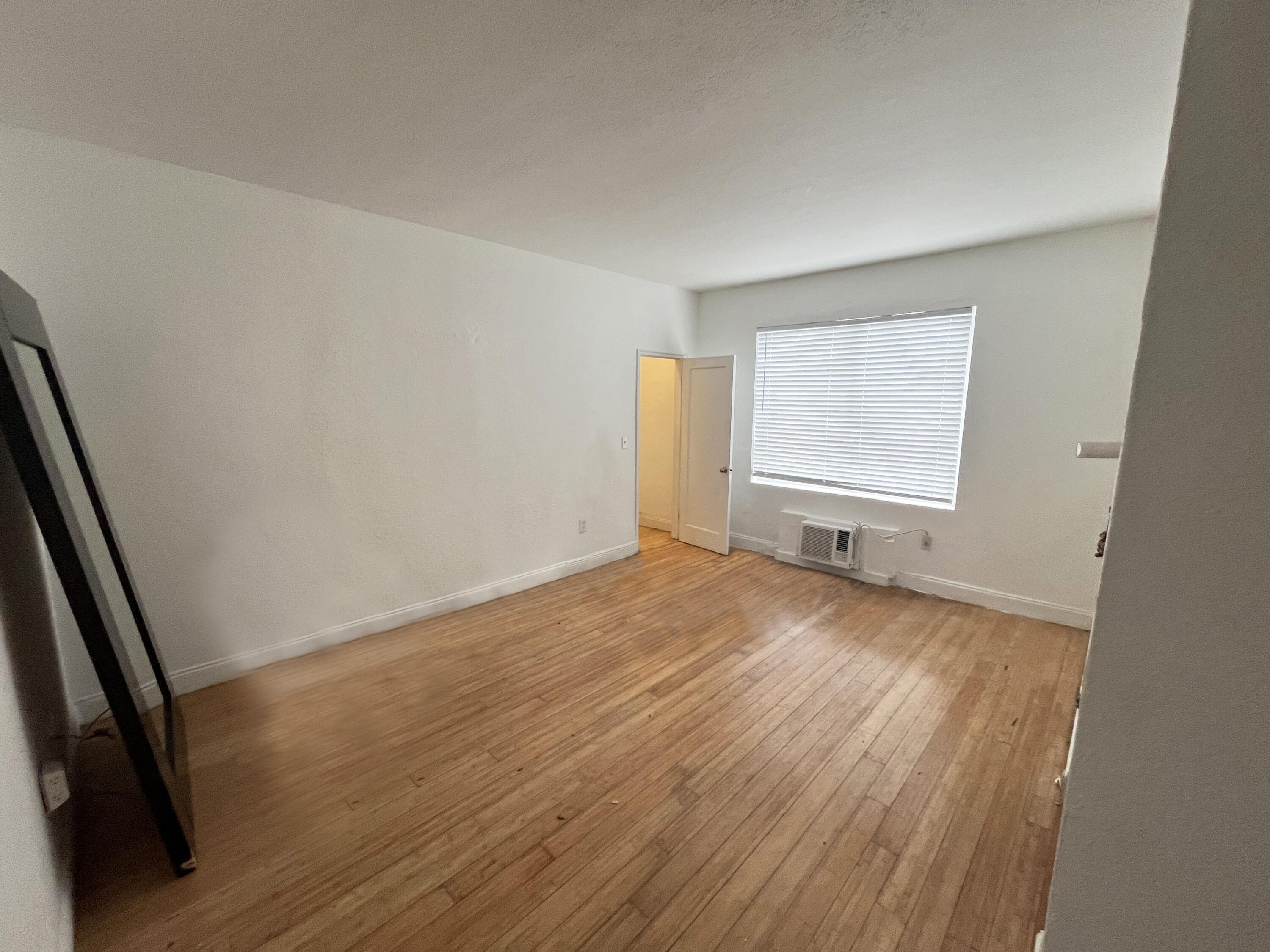320 80th Street, Unit 4 Miami Beach, FL 33141 - Photo 2 of 11 an empty room with wooden floor and windows